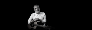 steve bell smiling with guitar in white shirt
